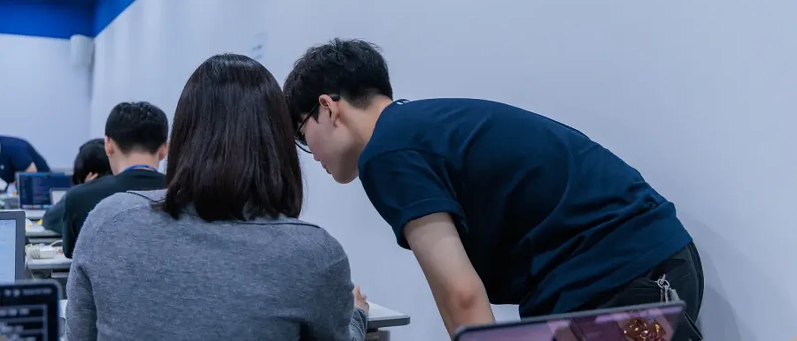 기업 AI 실습 교육 현장에서 강사가 수강생 옆에서 화면을 함께 보는 모습